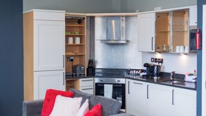 A compact kitchen with white cabinets, a built-in oven, and a coffee maker.