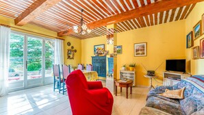 Uma sala de estar com uma poltrona vermelha, um sofá, uma televisão e um armário azul.