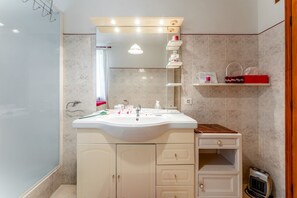 Een badkamer met een wastafel, spiegel, wastafelmeubel en een verwarming.