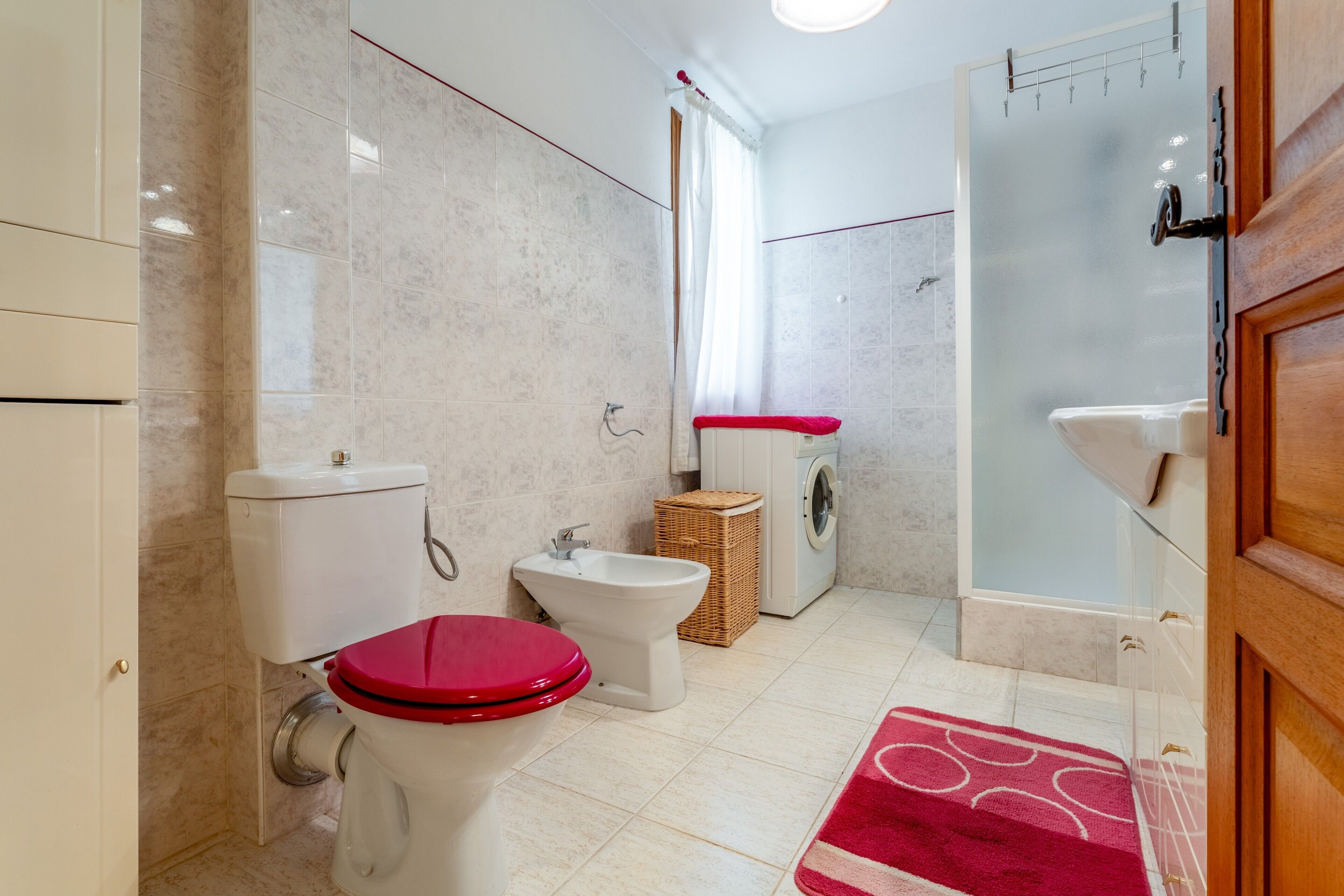 Een badkamer met toilet, bidet, wasmachine en douche.