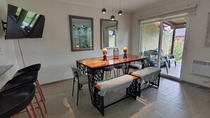 A dining area with a wooden table, black chairs, a bench, and a TV mounted on the wall. - Oceana Suites Los Nostros (Pucon)