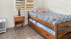 A single bed with a striped bedspread and a wooden nightstand with a lamp. - Oceana Suites Los Nostros (Pucon)