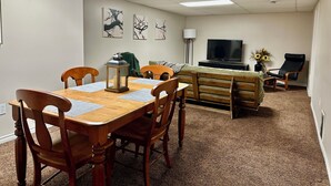 A dining area with a wooden table and chairs, a television, and artwork on the wall. - Beautiful Suite with Fenced yard + in suite Kitchen and Laundry (St. Albert)