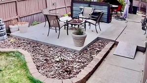 A patio with outdoor furniture, a potted plant, and a garden bed with mulch. - Beautiful Suite with Fenced yard + in suite Kitchen and Laundry (St. Albert)