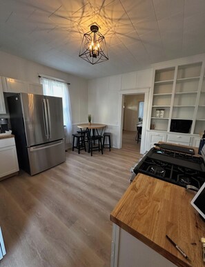 Eine moderne Küche mit einem Edelstahl-Kühlschrank, einer Holz-Kochinsel und einem eingebauten Herd.