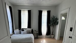 Une chambre à coucher avec un lit, un ventilateur de plafond et une plante en pot.
