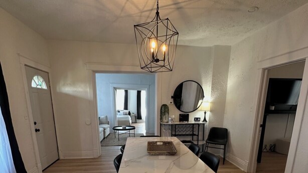 Une pièce spacieuse avec une grande table à manger, un luminaire suspendu et une vue sur une autre pièce.