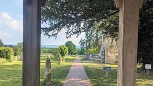 A pathway leading to a stone building with a sign indicating a war memorial.