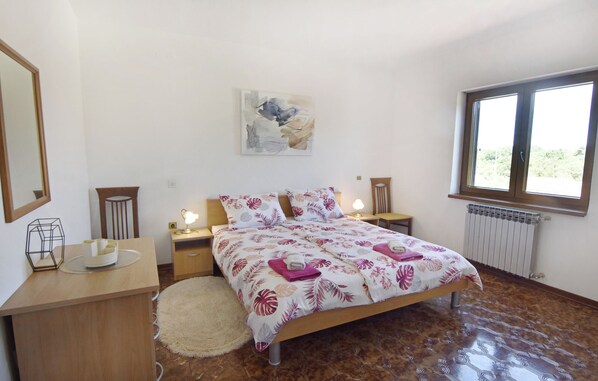 A bedroom with a bed, bedside tables, a nightstand, a mirror, a painting, and a window.