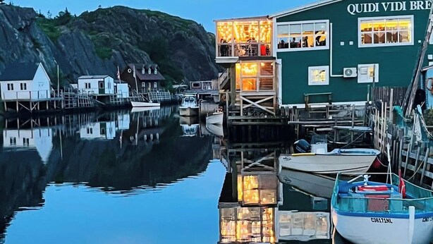 Um edifício à beira-mar com uma placa que diz "QUIDI VIDI BRE" e um cais com barcos.