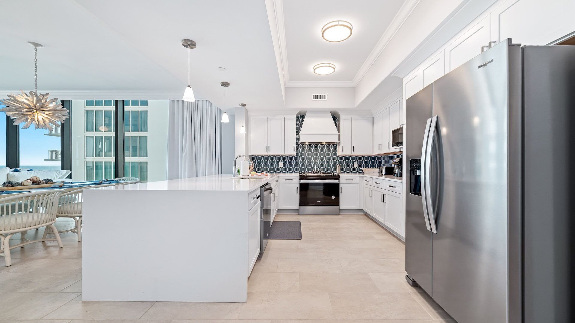 A modern kitchen with a central island, stainless steel appliances, and a view to the outside.