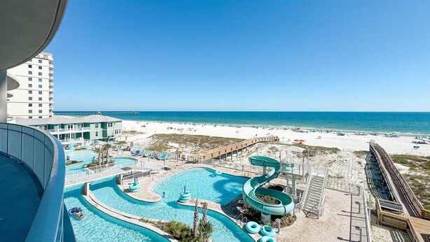 Et resort med en stor swimmingpool, vandrutsjebaner og udsigt til stranden.