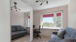 Una sala de estar moderna con un sofá gris, una silla de escritorio negra y piso de madera.