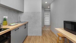 Una cocina moderna con armarios grises, encimera de madera, microondas y un taburete de madera.