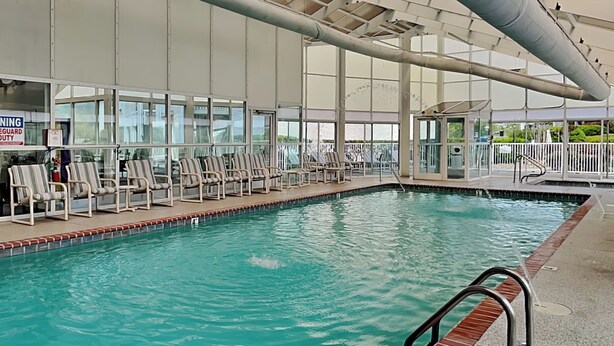 An indoor swimming pool with clear water, surrounded by lounge chairs and a covered seating area. - Prime Pines | Great Views, Great Location, Resort Amenities (Pigeon Forge)
