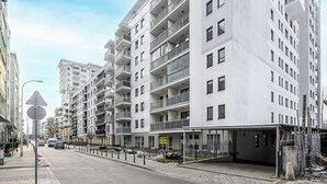 A multi-story residential building with balconies, a covered entrance, and a clear sky. - P&O Apartments PORY (Warsaw)