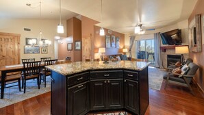 A spacious kitchen with dark cabinetry, a granite countertop, and pendant lighting.