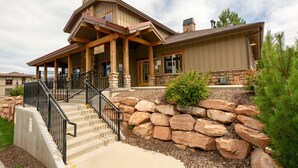 A two-story house with a stone foundation, a covered porch, and a staircase leading to the entrance.