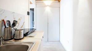A modern kitchen with a wooden ceiling, a white countertop, and a sink. There are stainless steel containers with utensils on the counter. - Duomo Studio Room with Private Bath and Kitchenette (Firenze)