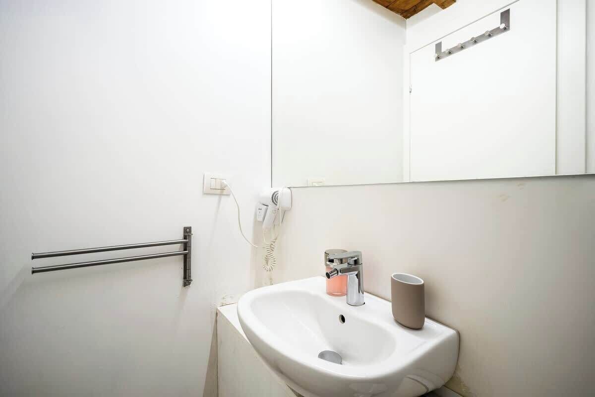 Ein helles Badezimmer mit Waschbecken, Handtuchhalter und Spiegel.