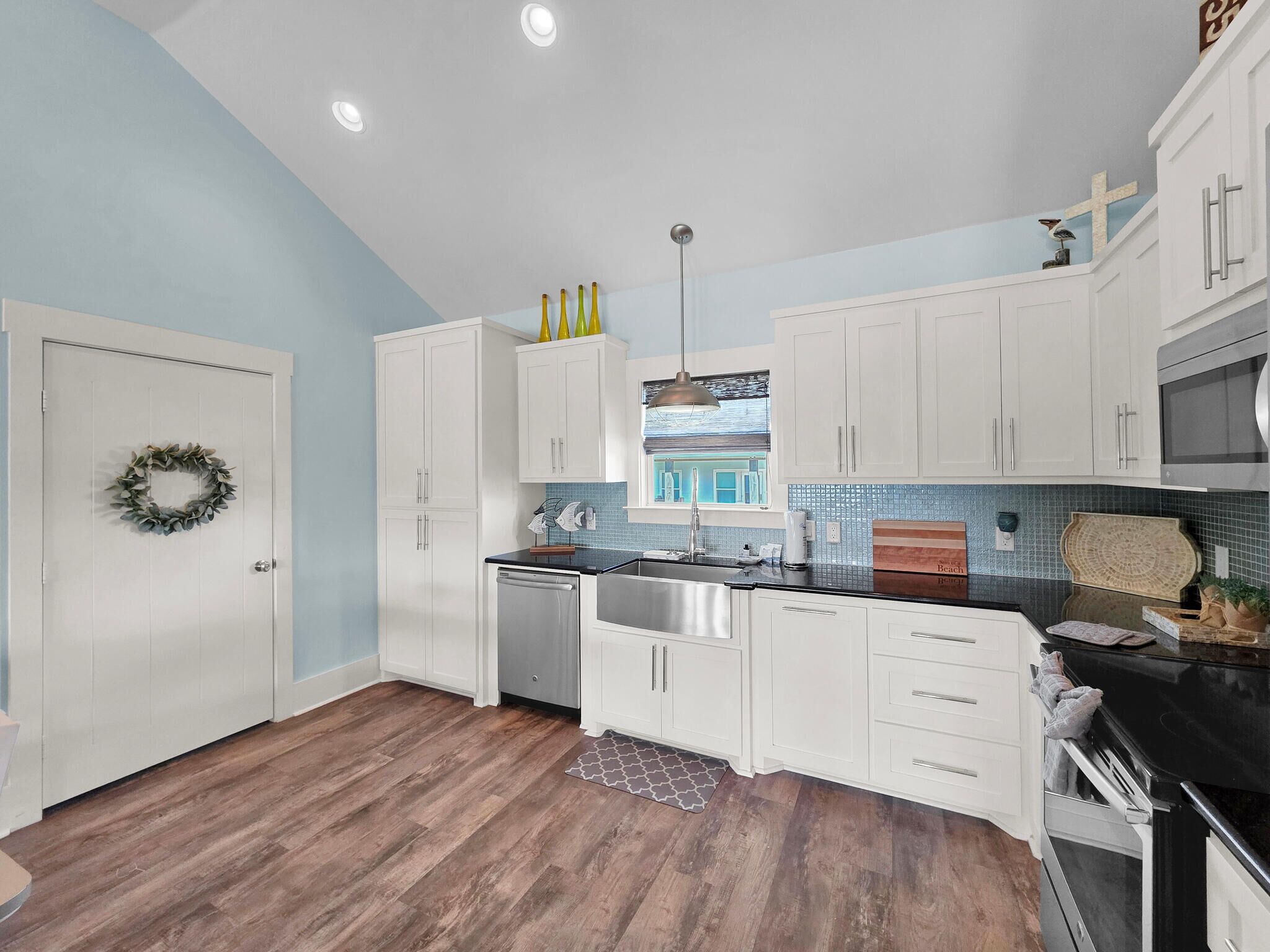 A modern kitchen with white cabinets, a stainless steel sink, and a black countertop.