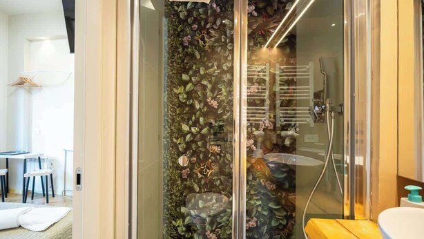 A modern bathroom with a glass shower enclosure, a wooden bench, and a white sink. - Duomo Room with Private Bath, WiFi and Netflix (Firenze)
