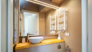 A modern bathroom with a large mirror, a white sink, and a towel rack. - Duomo Room with Private Bath, WiFi and Netflix (Firenze)