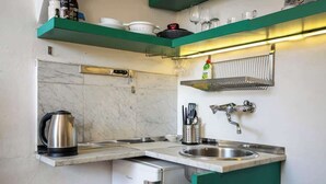 Une cuisine compacte équipée d’un lave-vaisselle intégré, d’une bouilloire et d’un évier.