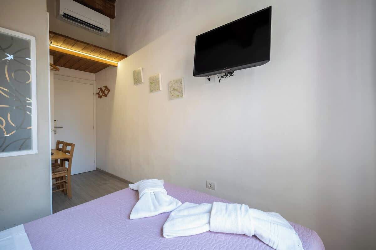 Une chambre d’hôtel équipée d’un lit, d’un téléviseur à écran plat fixé au mur et d’une porte donnant accès à une salle de bain.