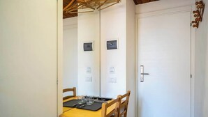 A dining area with a wooden table and chairs, a white door, and a ceiling with wooden beams. - Private Duomo Room with Ensuite Bath (Firenze)