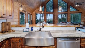 A kitchen with a large island, wooden cabinets, and a view of the outdoors. - Morning Glory - Cherry Log GA (Cherry Log)