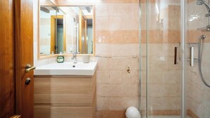 Een badkamer met een wastafel, spiegel en douche.