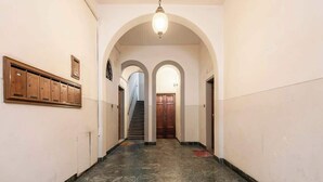 A hallway with a marble floor, wooden lockers, and a staircase leading to a door.