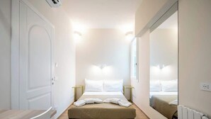 Une chambre d’hôtel comprenant un lit, des tables de chevet, une chaise, un miroir et un radiateur.