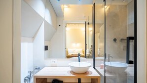 Une salle de bain moderne avec un grand miroir, un meuble-lavabo en bois, un lavabo blanc et une baignoire séparée.