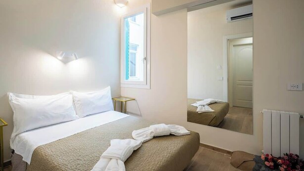 Une chambre d’hôtel avec un lit, une table de chevet, un miroir et une fenêtre.