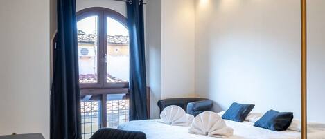 Une chambre d’hôtel avec un lit, un bureau, une chaise et une grande fenêtre avec des rideaux.