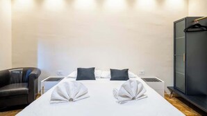A hotel room with a bed, two pillows, a bedside table, a wardrobe, and a chair. - Central Florence Room w/ Wi-Fi & Pvt Bath (Firenze)