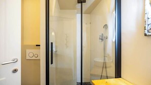 A modern bathroom with a glass shower enclosure, a wooden bench, and a toilet. - Central Florence Room w/ Wi-Fi & Pvt Bath (Firenze)