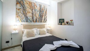 Une chambre d’hôtel avec un lit, des lampes de chevet, un climatiseur fixé au mur et un tableau au-dessus du lit.