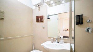 Une salle de bain avec un lavabo blanc, un miroir et des toilettes.
