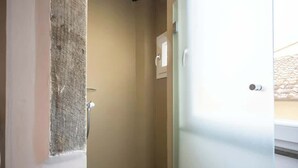 A small, enclosed bathroom with a shower, a door, and a visible light switch.