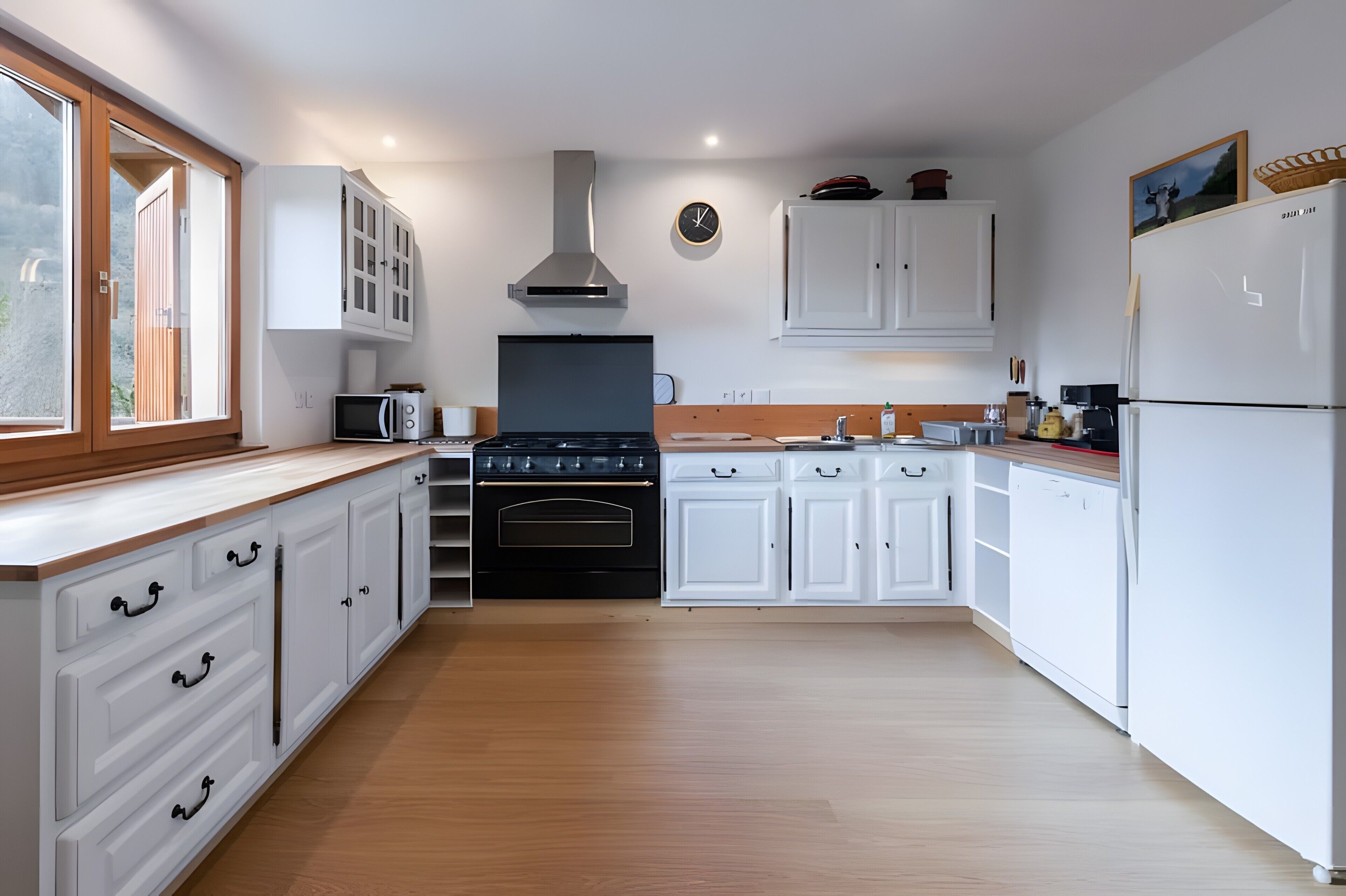 Een moderne keuken met witte kasten, een zwarte kookplaat en een magnetron.