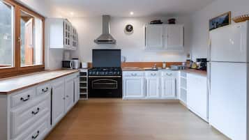Een moderne keuken met witte kasten, een zwarte kookplaat en een magnetron.