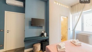 A modern hotel room with a flat-screen TV, a small seating area with a coffee machine, a bed with towels, and a window with curtains. - Victoria rooms  (Rome)