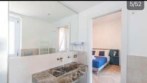 A modern bathroom with a marble sink, a mirror, and a towel rack. - Victoria rooms  (Rome)