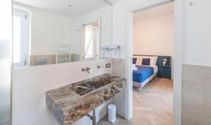 A modern bathroom with a marble sink, a mirror, and a towel rack. - Victoria rooms  (Rome)