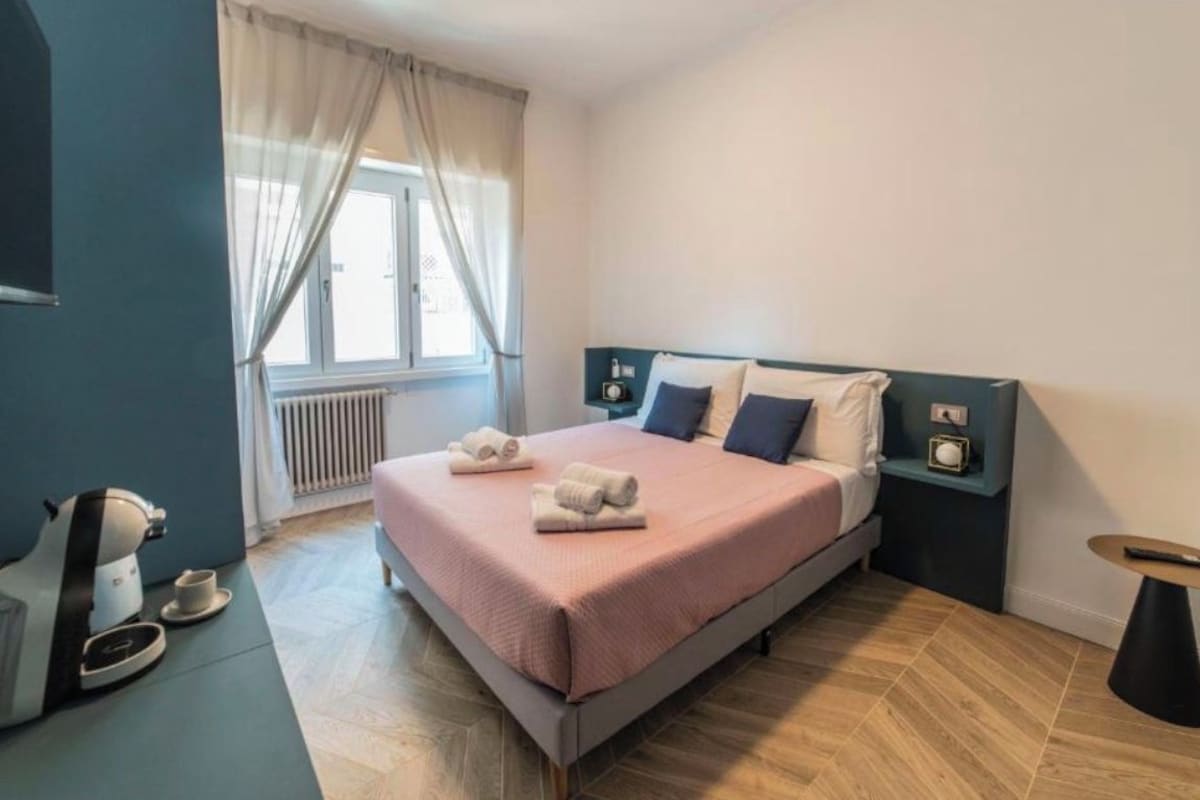 A modern hotel room with a bed, a coffee machine, and a small table.