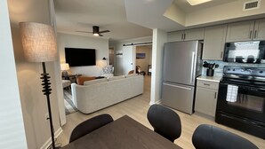 A modern kitchen with a refrigerator, stove, and microwave. There is a dining area with a table and chairs. - 504 Brighton 2 Bedroom Condo (Myrtle Beach)