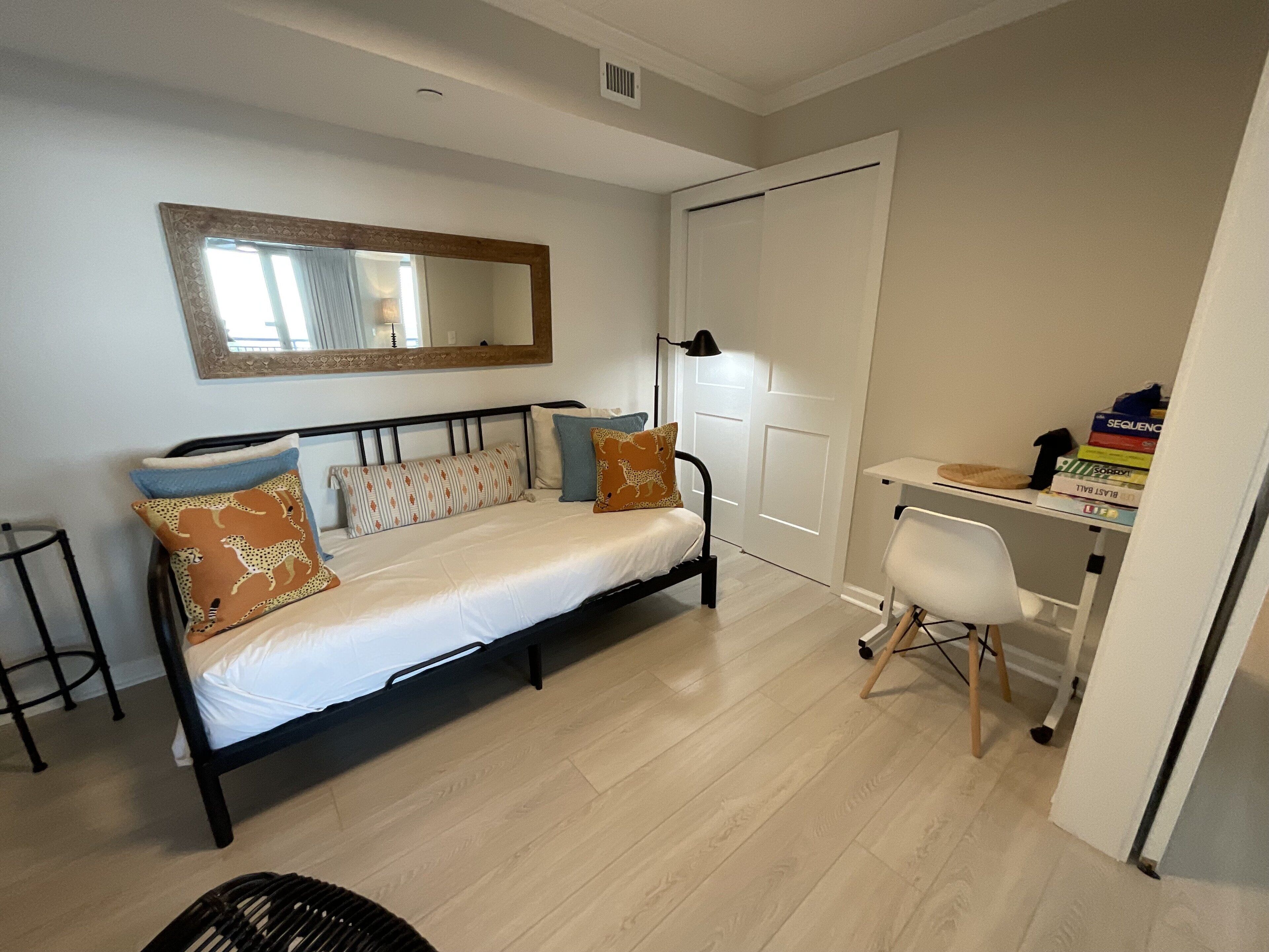 A bedroom with a bed, a desk, and a chair.